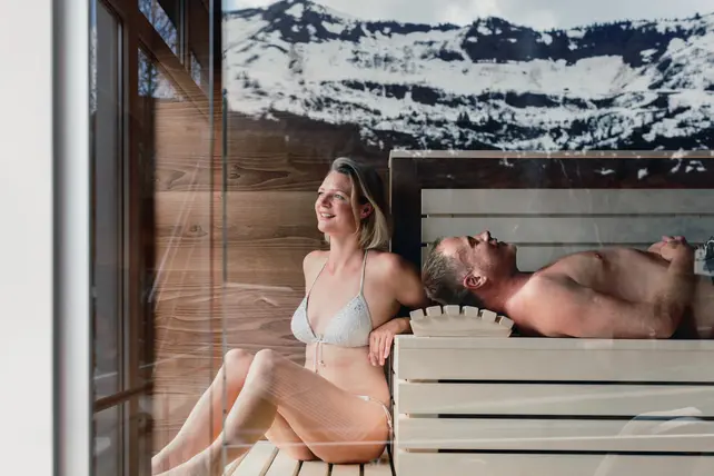 Paar in der Sauna mit Blick auf schneebedeckte Berge