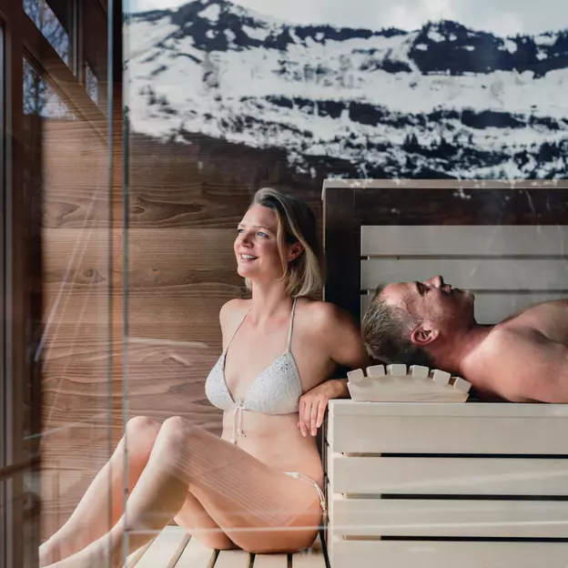 Paar in der Sauna mit Blick auf schneebedeckte Berge